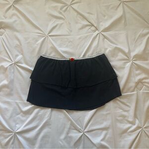 Black ruffle mini skirt with white lace trim and a red rosette